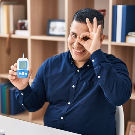 A diabetic patient holding a glucometer and holding their hand in a circle around their eye